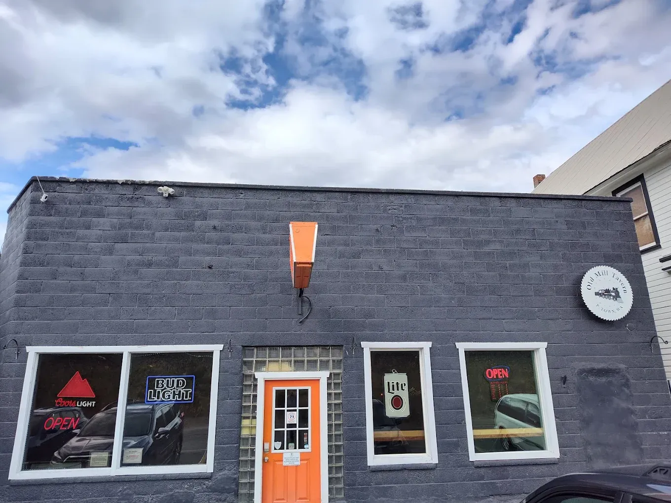Dark gray exterior of Old Mill Tavern with its orange front door in Peshastin, WA