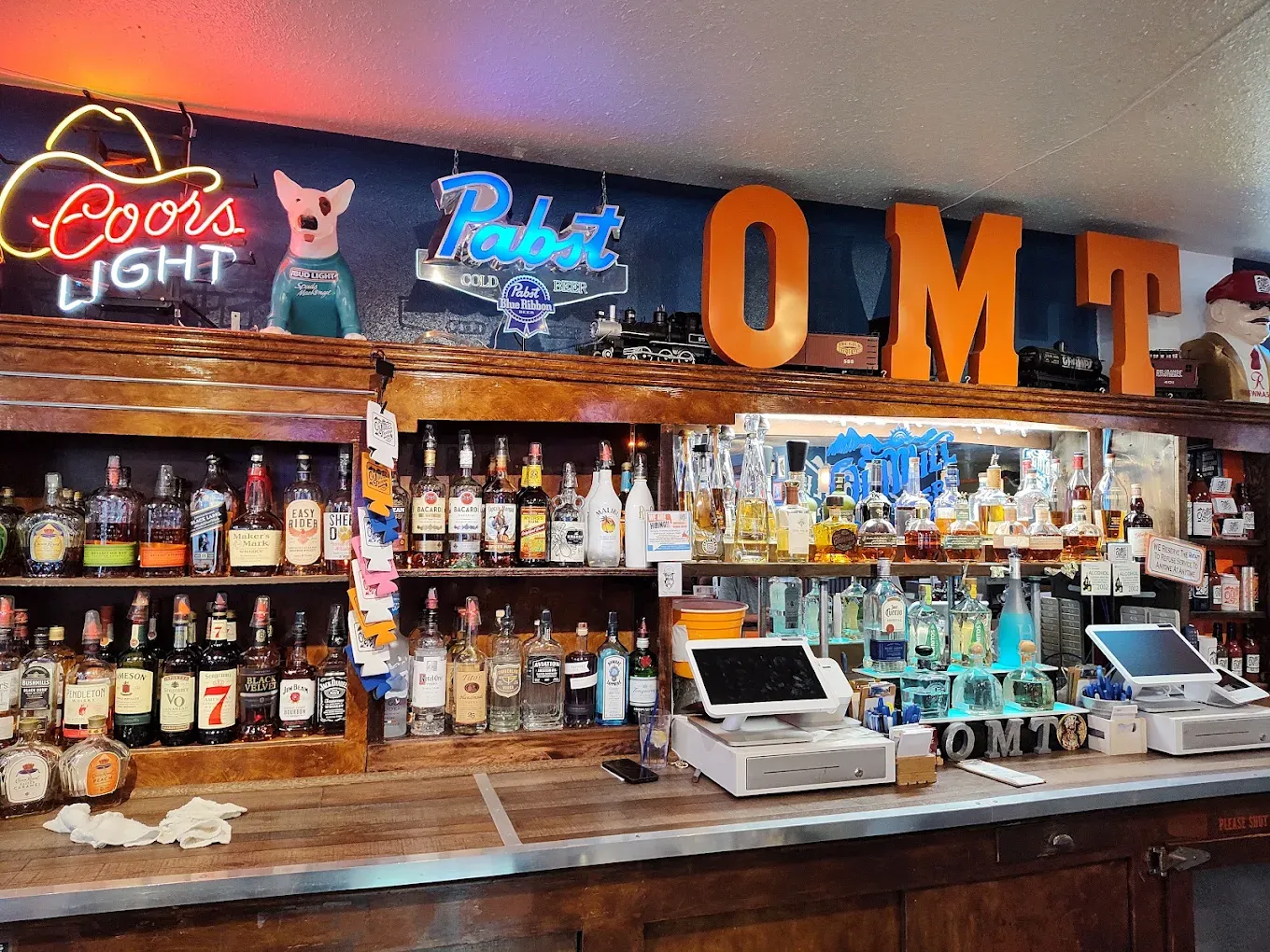 Full back bar with lit OMT letters and neon signs at Old Mill Tavern in Peshastin, WA